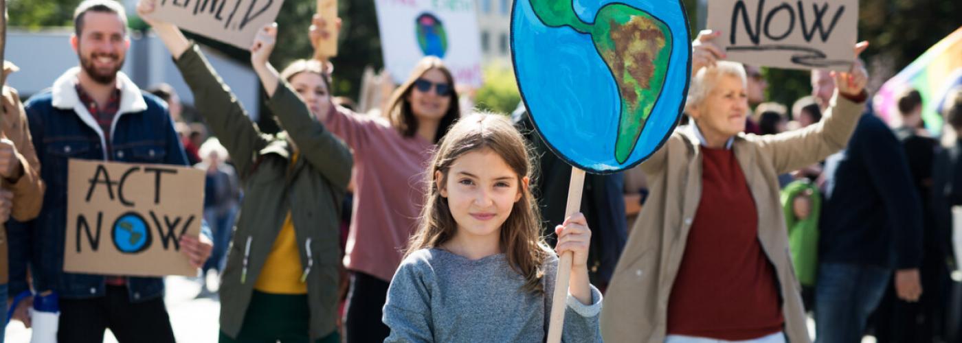 A young girl holds a handmade sign of the Earth at a climate protest