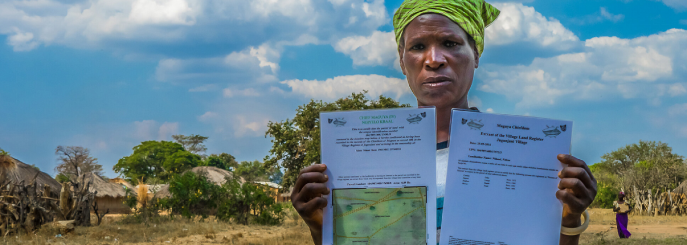 A woman looks at the camera while holding two documents