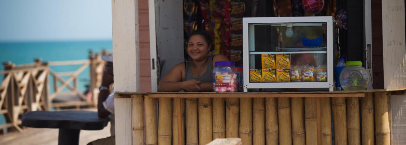 Photo: Woman standing in a hut stand selling items.