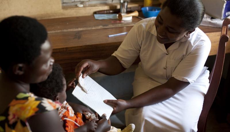 Prior to the pandemic, a nurse reviews health information with a mother and her child in Uganda. / Health Partners
