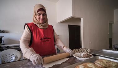 A woman rolls out dough in a kitchen