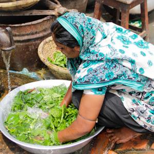 A woman washes lettuce outside her home at Amin Bazaar in Mirpur, Bangladesh. Photo: Lindsay Seuc