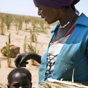 woman working in agriculture with her child beside her