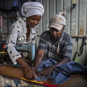 A man and woman work with a sewing machine