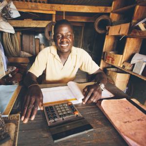 A man smiles at the camera as he runs a hardware shop in Kalangala