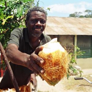 Photo: Man holding a coconut, facing the camera